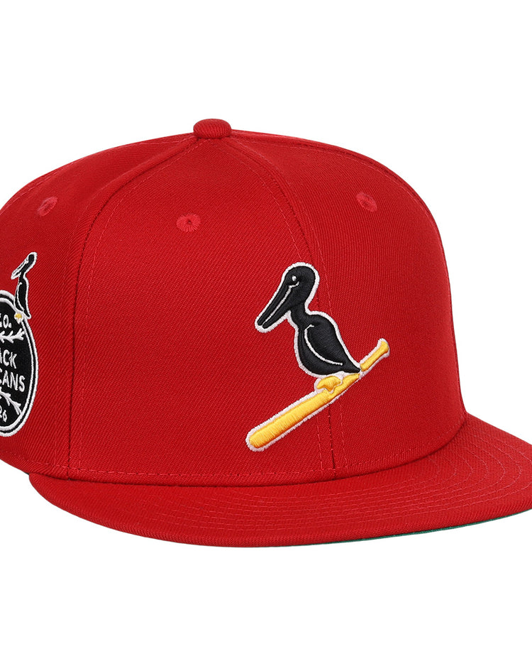 The EFF New Orleans Black Pelicans NLB Team Color Fitted Ballcap in red features a black pelican on a yellow bat, a side patch with New Orleans Black Pelicans 1922, and honors the Negro Southern League with an added small pelican graphic.