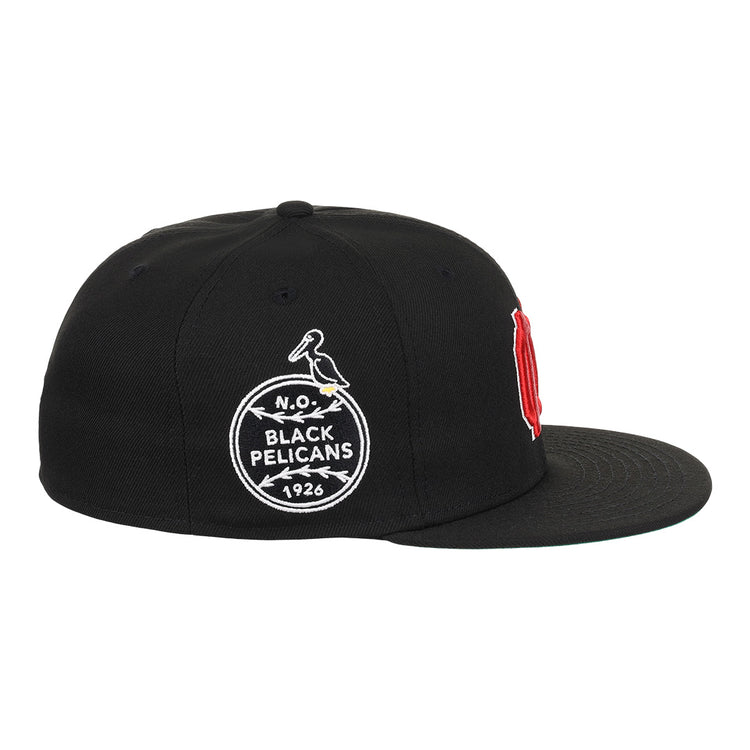 The EFF New Orleans Black Pelicans NLB Team Color Fitted Ballcap in black features a vintage-style circular pelican patch with “N.O. Black Pelicans 1926” and a red embroidered letter visible from the front side, honoring the historic team.