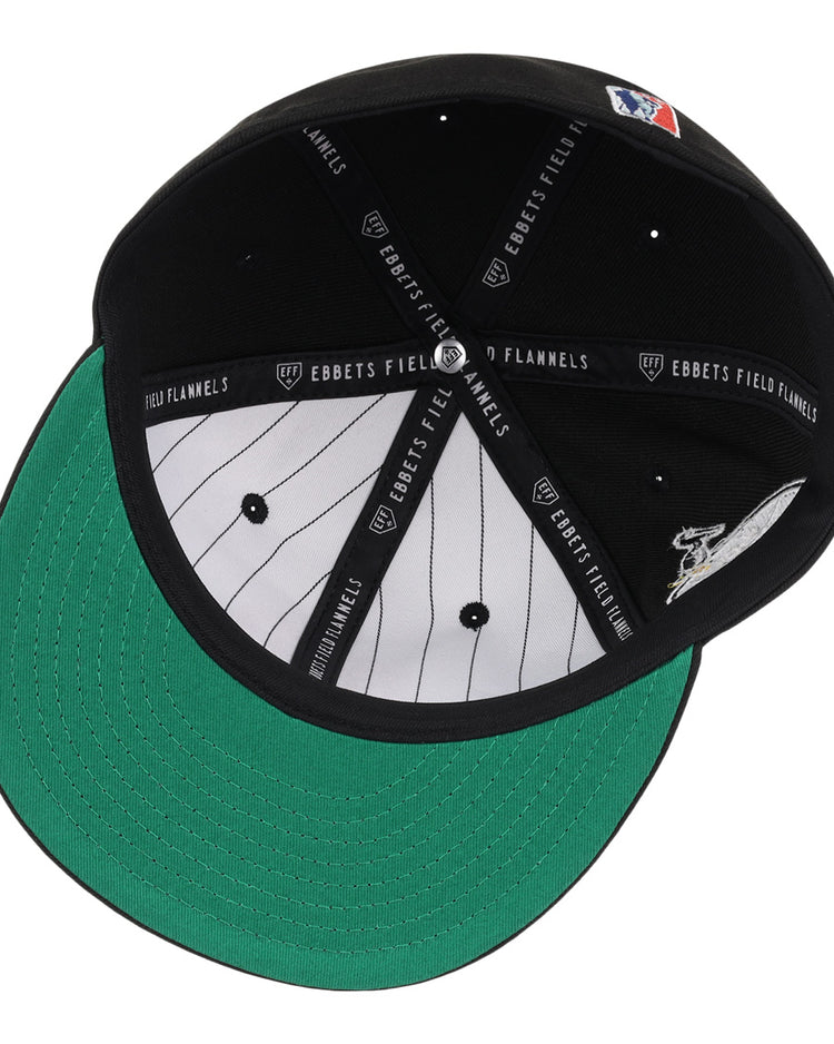 The EFF New Orleans Black Pelicans NLB Team Color Fitted Ballcap in black is shown from below, highlighting its green bill, white pinstriped lining, and EBBETS FIELD FLANNELS text on the black inner seams.