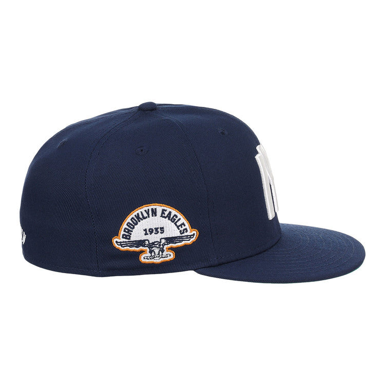 The EFF Brooklyn Eagles NLB Team Color Fitted Ballcap features a navy blue flat-brim design with bold NY embroidery up front and a 1935 Brooklyn Eagles patch with eagle logo on the side, perfect for collectors seeking vintage style.