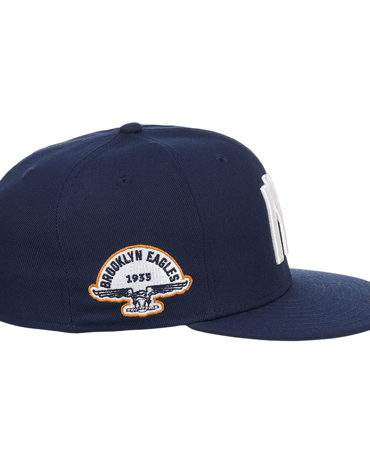 The EFF Brooklyn Eagles NLB Team Color Fitted Ballcap features a navy blue flat-brim design with bold NY embroidery up front and a 1935 Brooklyn Eagles patch with eagle logo on the side, perfect for collectors seeking vintage style.