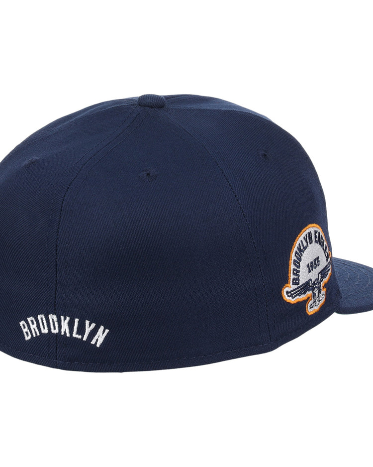 The EFF Brooklyn Eagles NLB Team Color Fitted Ballcap features a navy blue design, white BROOKLYN embroidery on the back, a circular Brooklyn Eagles patch on the side, and classic vintage-inspired details.
