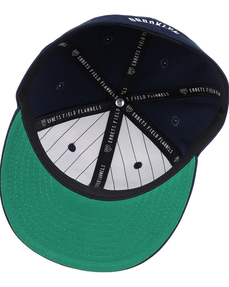 A navy Brooklyn Eagles NLB Team Color Fitted Ballcap by EFF, seen from below with a green underbrim, black and white pinstriped lining, and EBBETS FIELD FLANNELS printed on the inner seams.