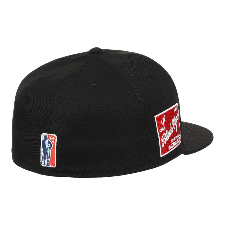 The EFF Louisville Black Caps NLB Team Color Fitted Ballcap is a black vintage cap with an embroidered blue and white silhouette patch on the left and a red and white patch on the back, celebrating the Negro National League legacy.