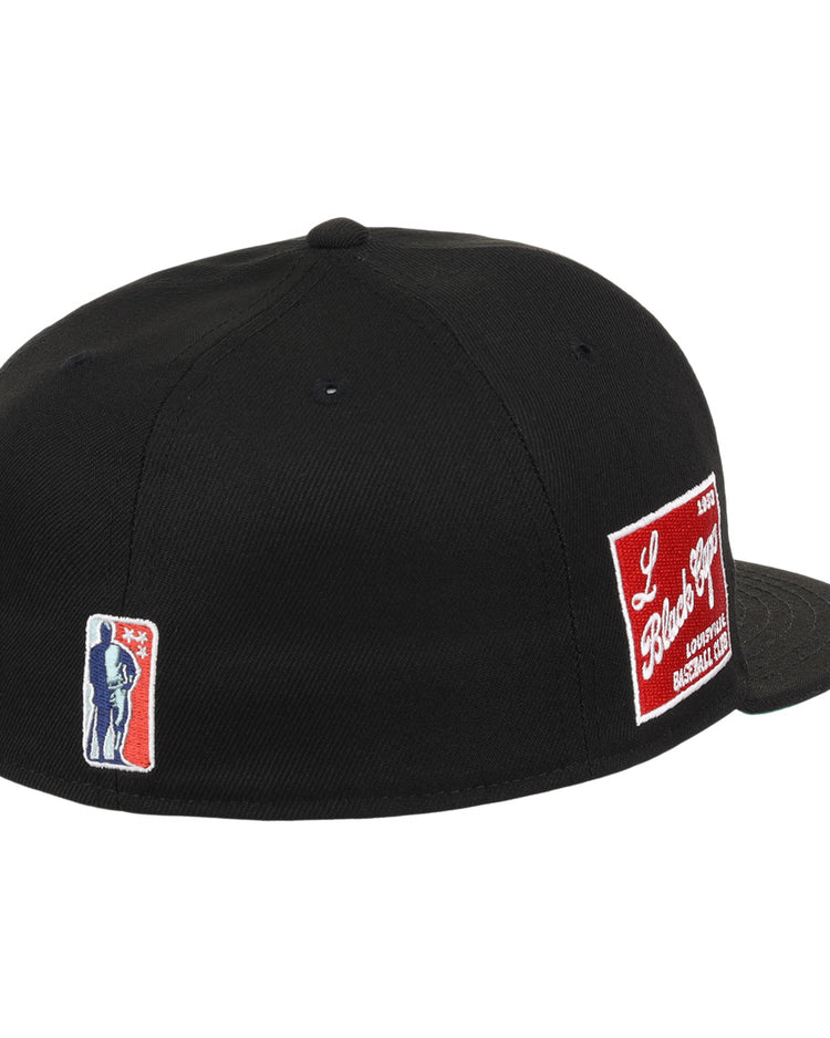 The EFF Louisville Black Caps NLB Team Color Fitted Ballcap is a black vintage cap with an embroidered blue and white silhouette patch on the left and a red and white patch on the back, celebrating the Negro National League legacy.