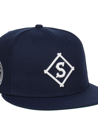 The EFF Seattle Steelheads NLB Team Color Fitted Ballcap is a vintage-inspired navy hat with a white diamond S embroidered logo on the front and a circular patch with text and graphics on the side.