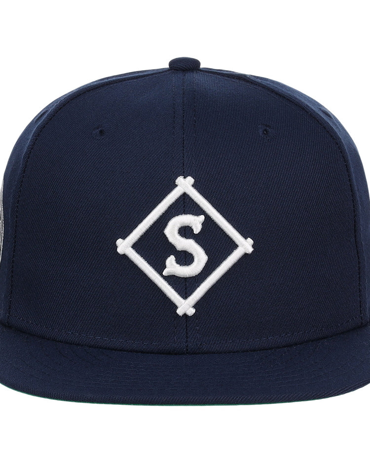 The EFF Seattle Steelheads NLB Team Color Fitted Ballcap features a navy blue design with a flat brim and an embroidered white “S” inside a diamond on the front.