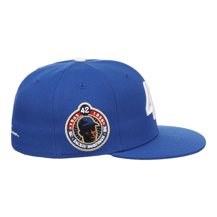 The EFF Jackie Robinson EFF Signature Series Fitted Ballcap - Royal features a blue design with a white button, white embroidered “LA” on the front, and a side patch with Jackie Robinson’s silhouette and number 42.
