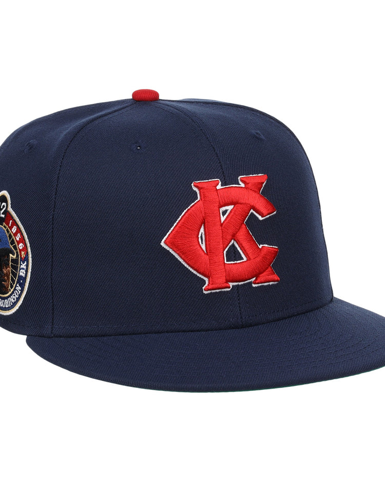The EFF Kansas City Monarchs Robinson Fitted Ballcap in navy features a red embroidered KC logo, a Jackie Robinson #42 patch on the side, and a bold red button on top.
