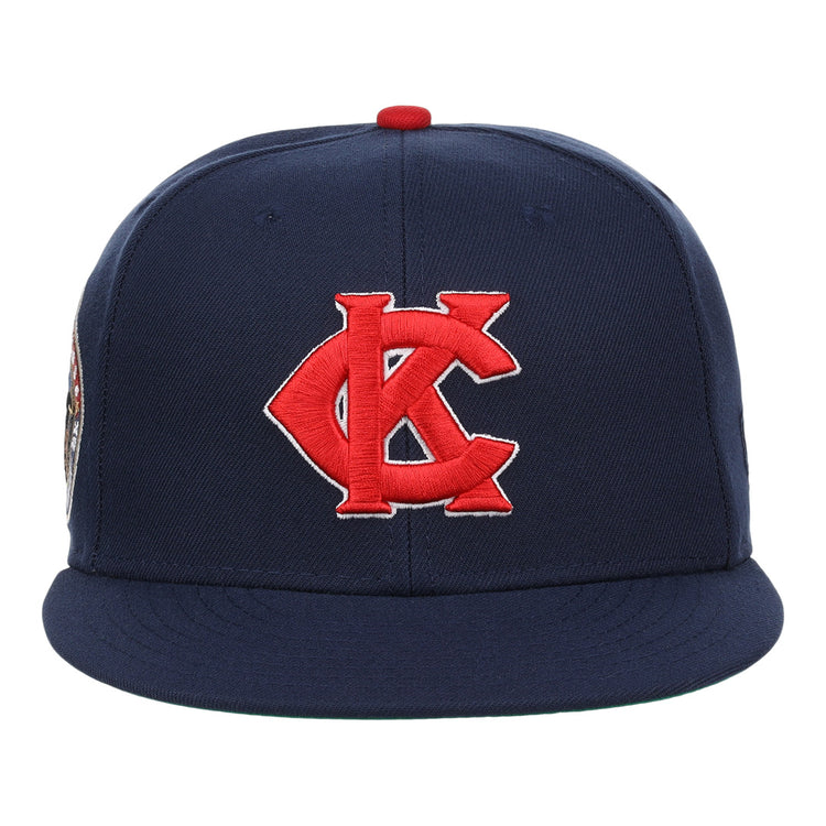 The EFF Kansas City Monarchs Robinson Fitted Ballcap in navy features a red and white embroidered KC logo on the front, inspired by Jackie Robinson’s iconic cap, and is finished with a red top button.