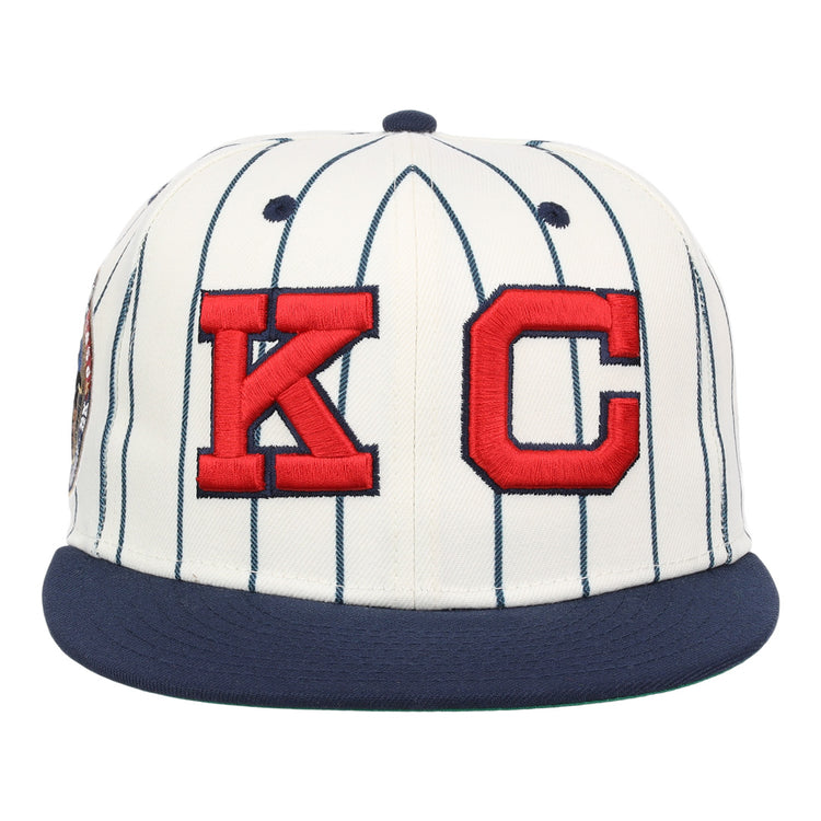 The EFF Kansas City Monarchs Robinson Pinstripe Fitted Ballcap features a white base with dark blue pinstripes, a dark blue brim, and a bold embroidered KC logo on the front—showcasing signature series style.