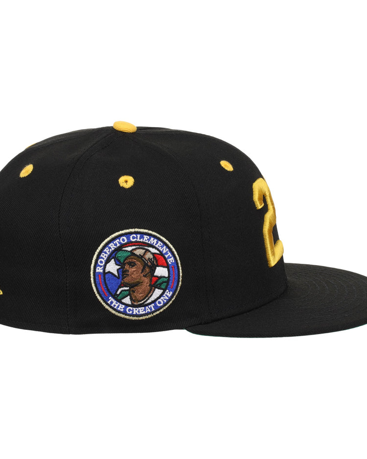 The EFF Roberto Clemente Signature Series Fitted Ballcap in black features yellow accents, a bold yellow 21 on the side, and a circular patch with Clemente’s portrait and “The Great One.”.
