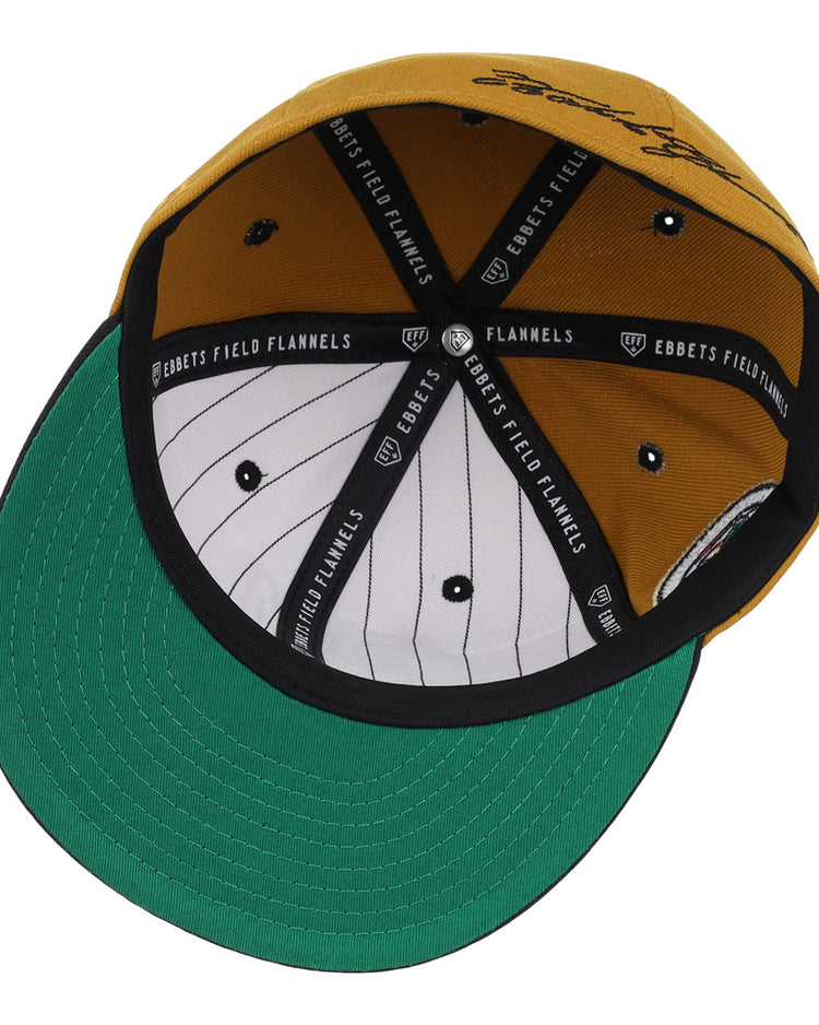 The EFF Roberto Clemente Signature Series Fitted Ballcap in gold features a green underbill, black and white pinstriped inner lining, black trim with EBBETS FIELD FLANNELS text, and classic 3D embroidered details.