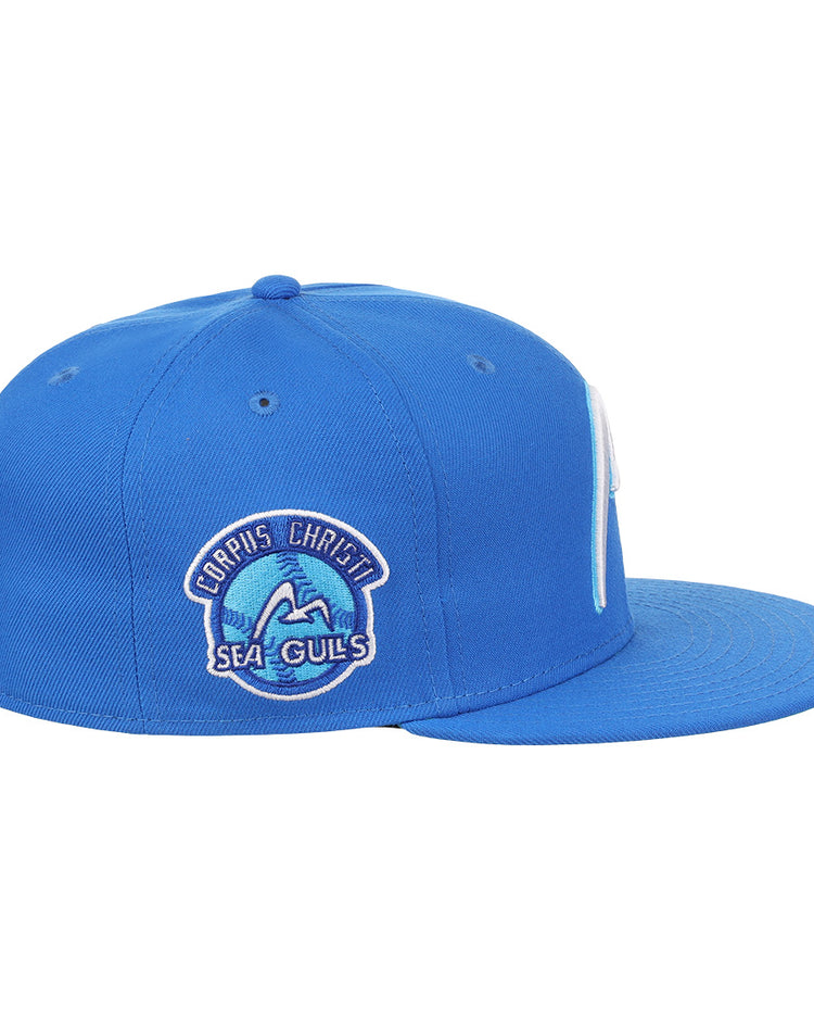 The EFF Corpus Christi Seagulls Lone Star Fitted Ballcap is a blue cap with a flat brim and side patch featuring “Corpus Christi Sea Gulls” with a wave and seagull, honoring the iconic Lone Star League team.