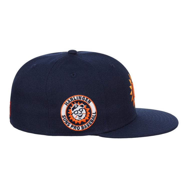 The EFF Harlingen Suns EFF Lone Star Fitted Ballcap is a navy ballcap with a 3D orange sun logo on the front and a side patch reading “Harlingen Suns Pro Baseball” with a cartoon sun. Part of the Lone Star League collection.