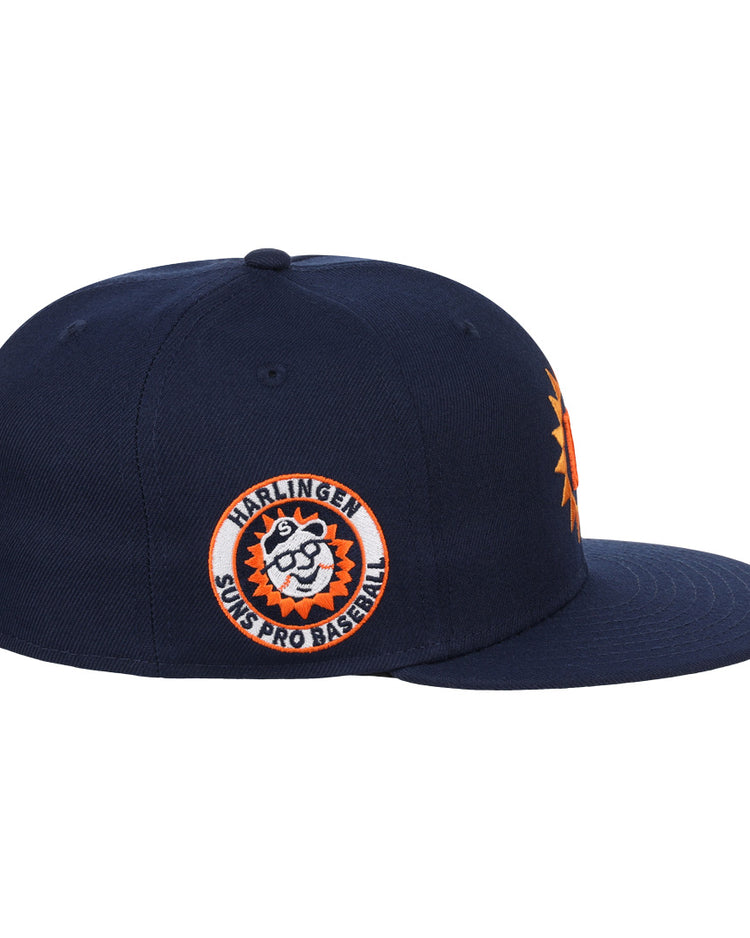 The EFF Harlingen Suns EFF Lone Star Fitted Ballcap is a navy ballcap with a 3D orange sun logo on the front and a side patch reading “Harlingen Suns Pro Baseball” with a cartoon sun. Part of the Lone Star League collection.