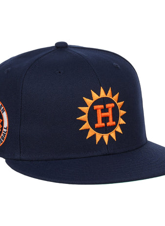 The Harlingen Suns EFF Lone Star Fitted Ballcap by EFF features a navy blue design with a 3D orange sun logo with a white H on the front, and a side patch of a smiling baseball and Harlingen Sunbirds Pro Baseball in the Lone Star League.