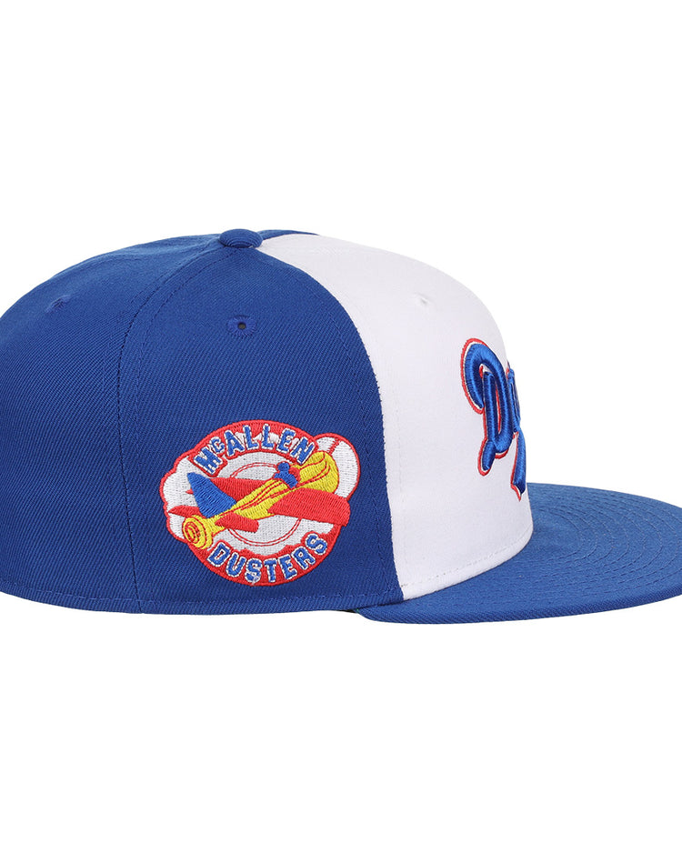 The EFF McAllen Dusters Lone Star Fitted Ballcap features blue and white panels, a flat blue brim, and a colorful yellow airplane patch with HEALEN DUSTERS embroidered, inspired by the classic Lone Star League team.