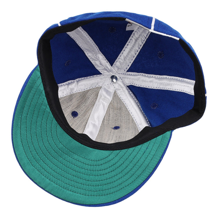 An overhead view of the open Almendares Alacranes 1931 Vintage Ballcap by Ebbets Field Flannels shows its white and blue panels, central metal button, and green underside of the brim.