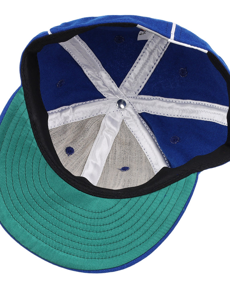 An overhead view of the open Almendares Alacranes 1931 Vintage Ballcap by Ebbets Field Flannels shows its white and blue panels, central metal button, and green underside of the brim.