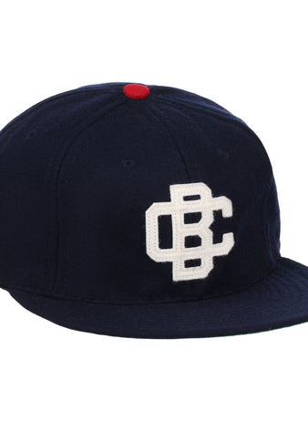 The Carta Blanca 1939 Vintage Ballcap by Ebbets Field Flannels features navy wool, a red top button, and a white embroidered CBC logo inspired by classic Mexican League style.