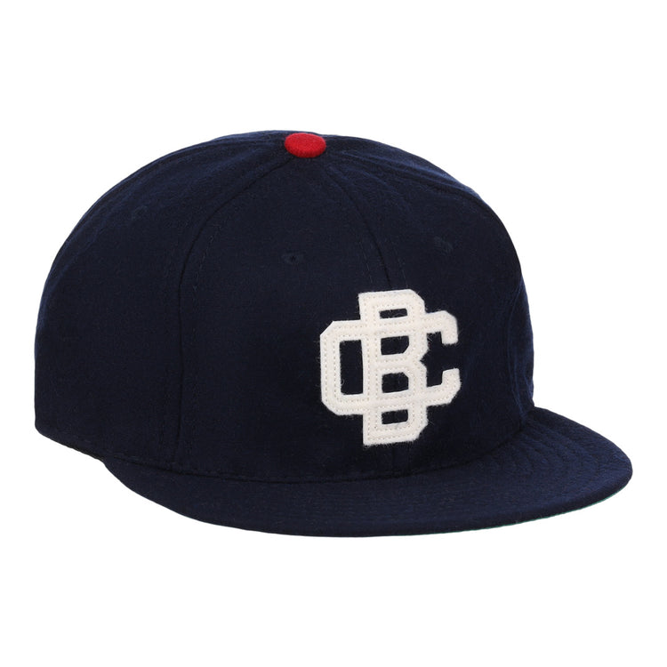 The Carta Blanca 1939 Vintage Ballcap by Ebbets Field Flannels features navy wool, a red top button, and a white embroidered CBC logo inspired by classic Mexican League style.