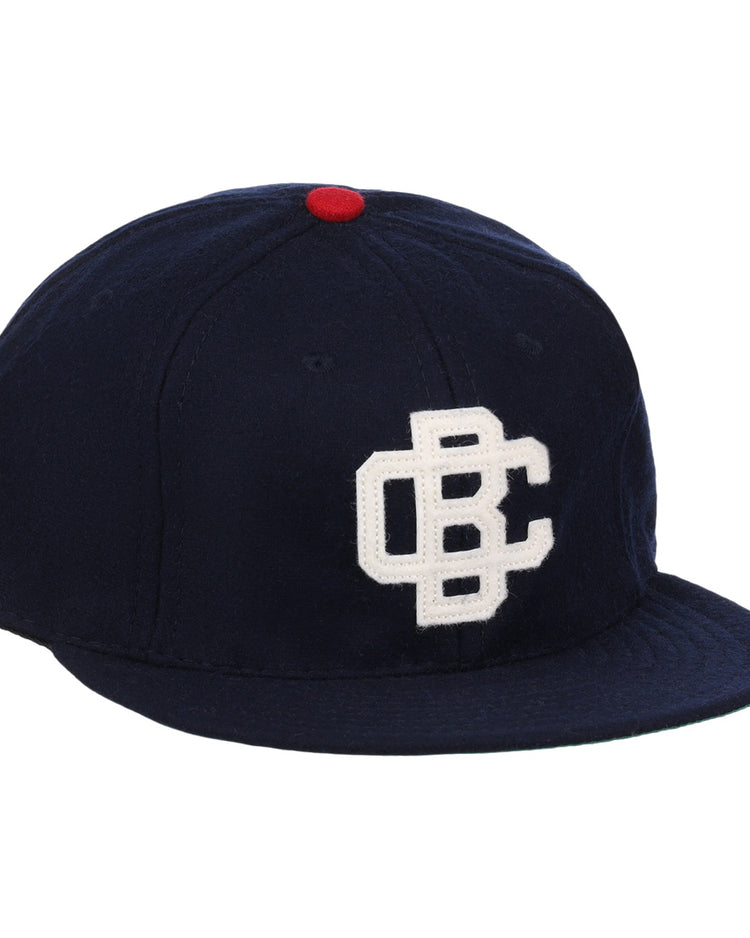 The Carta Blanca 1939 Vintage Ballcap by Ebbets Field Flannels features navy wool, a red top button, and a white embroidered CBC logo inspired by classic Mexican League style.