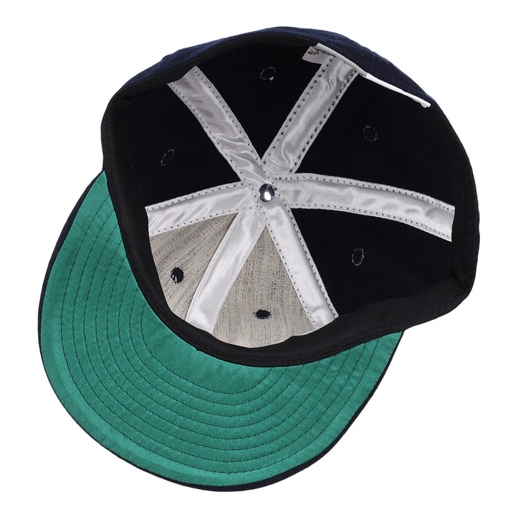 The image shows the inside of the Carta Blanca 1939 Vintage Ballcap by Ebbets Field Flannels, featuring a green underbrim, black sweatband, silver lining strips, and embroidered eyelets inspired by a classic Mexican League design.