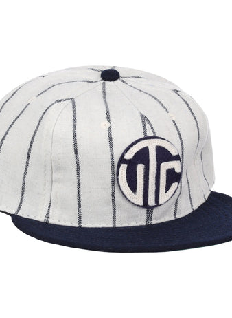 The Vedado TC 1930 Vintage Ballcap by Ebbets Field Flannels features thin vertical navy stripes, a navy brim, and a circular front patch with bold white UTC letters on navy, inspired by the classic Vedado TC ballcap.