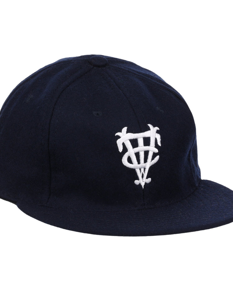 The Vedado TC 1945 Vintage Ballcap by Ebbets Field Flannels is a navy cap with a white interlocking letter logo, inspired by the Cuban National Amateur League, and features a curved brim and structured crown.