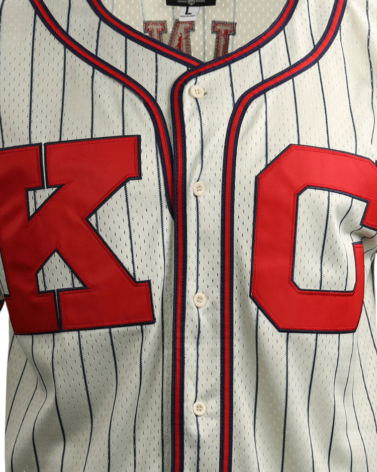 The EFF Jackie Robinson Kansas City Monarchs Vintage Inspired NL Replica Button-Up Mesh Jersey features white pinstripes, bold red “K” and “C” letters outlined in blue, capturing classic Negro National League style.