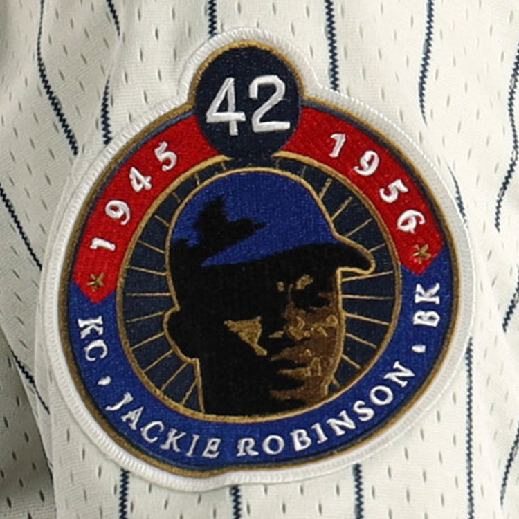 A patch on the EFF Jackie Robinson Kansas City Monarchs Vintage Inspired NL Replica Mesh Jersey shows #42, 1945 & 1956, a blue-capped player silhouette, and gold KC JACKIE ROBINSON BR text on the striped mesh background.