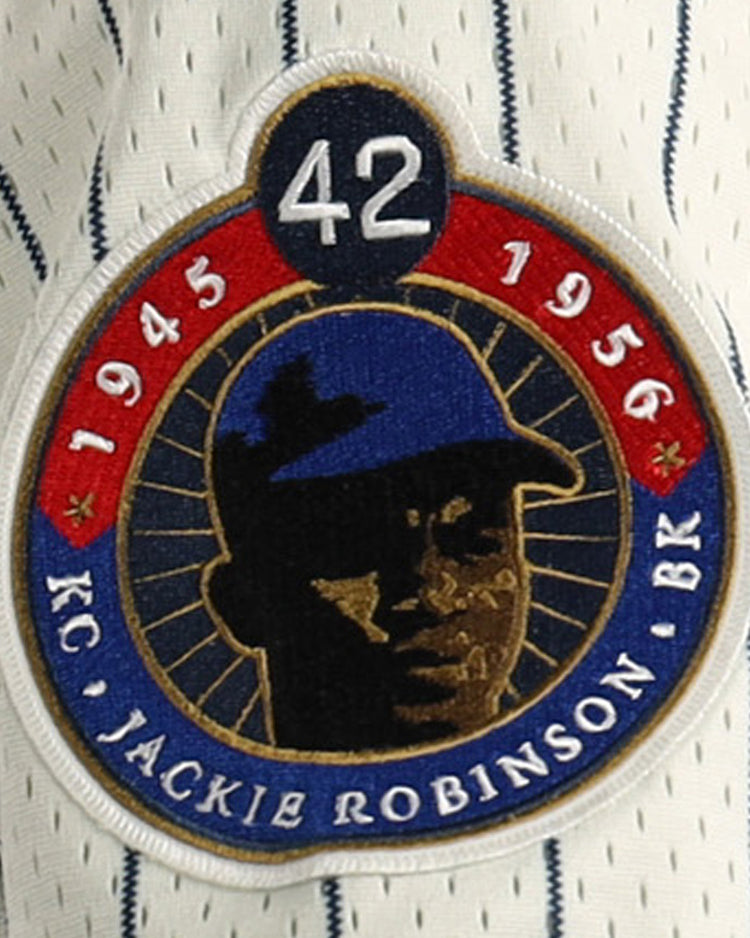 A patch on the EFF Jackie Robinson Kansas City Monarchs Vintage Inspired NL Replica Mesh Jersey shows #42, 1945 & 1956, a blue-capped player silhouette, and gold KC JACKIE ROBINSON BR text on the striped mesh background.