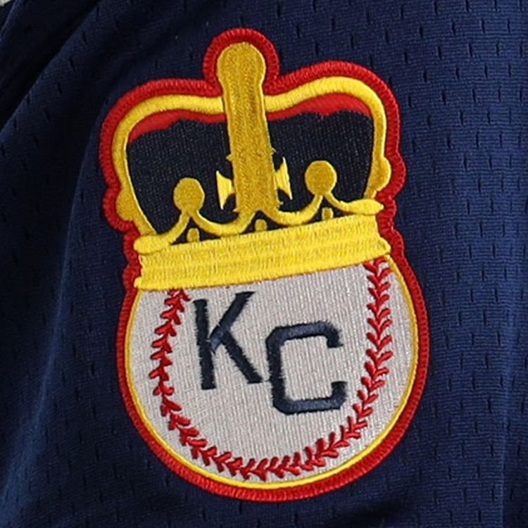 The EFF Jackie Robinson Kansas City Monarchs Vintage Inspired NL Replica V-Neck Mesh Jersey features an embroidered patch with a crowned, red-stitched baseball and KC lettering on dark blue mesh fabric.