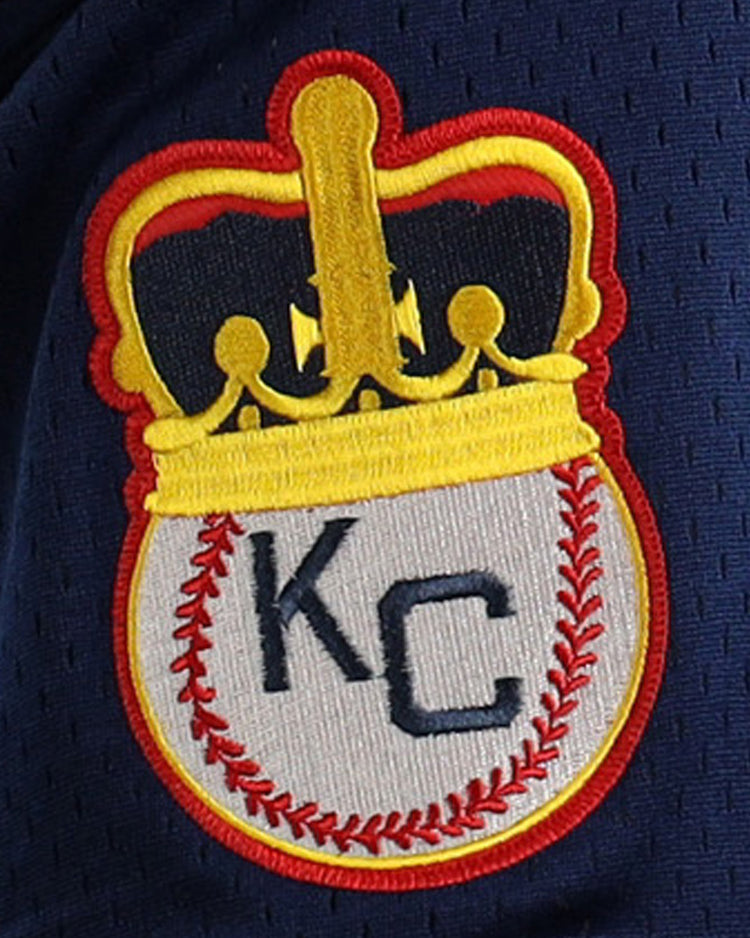 The EFF Jackie Robinson Kansas City Monarchs Vintage Inspired NL Replica V-Neck Mesh Jersey features an embroidered patch with a crowned, red-stitched baseball and KC lettering on dark blue mesh fabric.