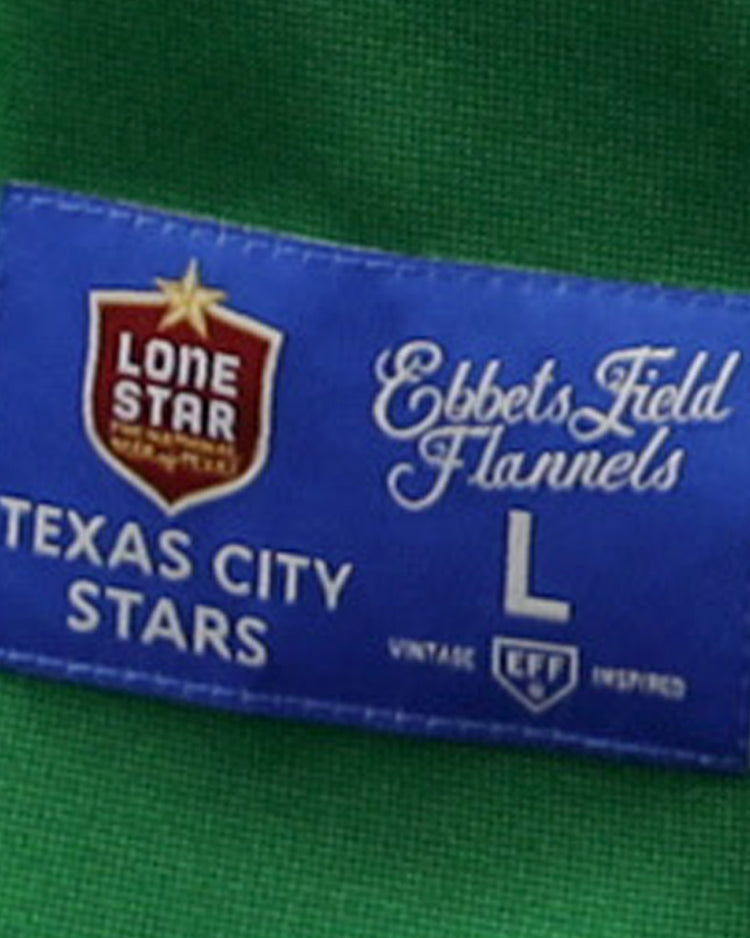 A blue fabric label on the green Texas City Stars EFF Lone Star Baseball Jersey by EFF reads Lone Star, Texas City Stars, EFF, L, and Vintage EFF Inspired with a star and shield logo—ideal for devoted baseball fans.
