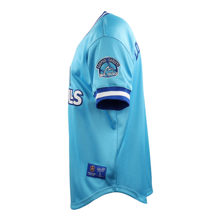 The EFF Corpus Christi Seagulls Lone Star Baseball Jersey features light blue fabric with white and blue trim, the team name on the front, and the Seagulls logo on the sleeve—celebrating Lone Star League heritage. Pictured from the side.