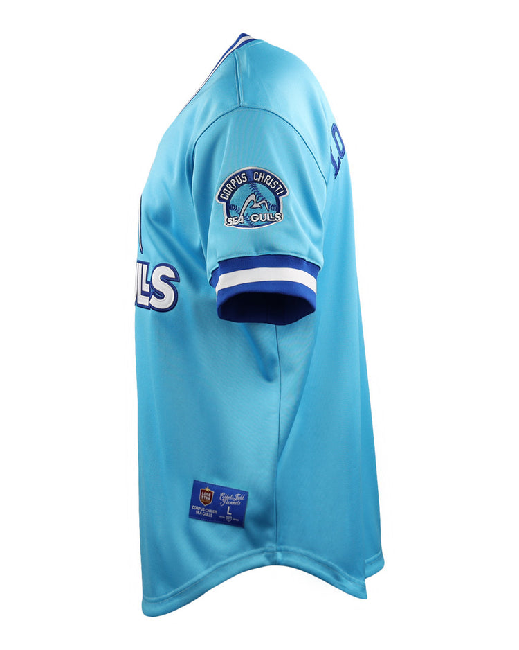 The EFF Corpus Christi Seagulls Lone Star Baseball Jersey features light blue fabric with white and blue trim, the team name on the front, and the Seagulls logo on the sleeve—celebrating Lone Star League heritage. Pictured from the side.