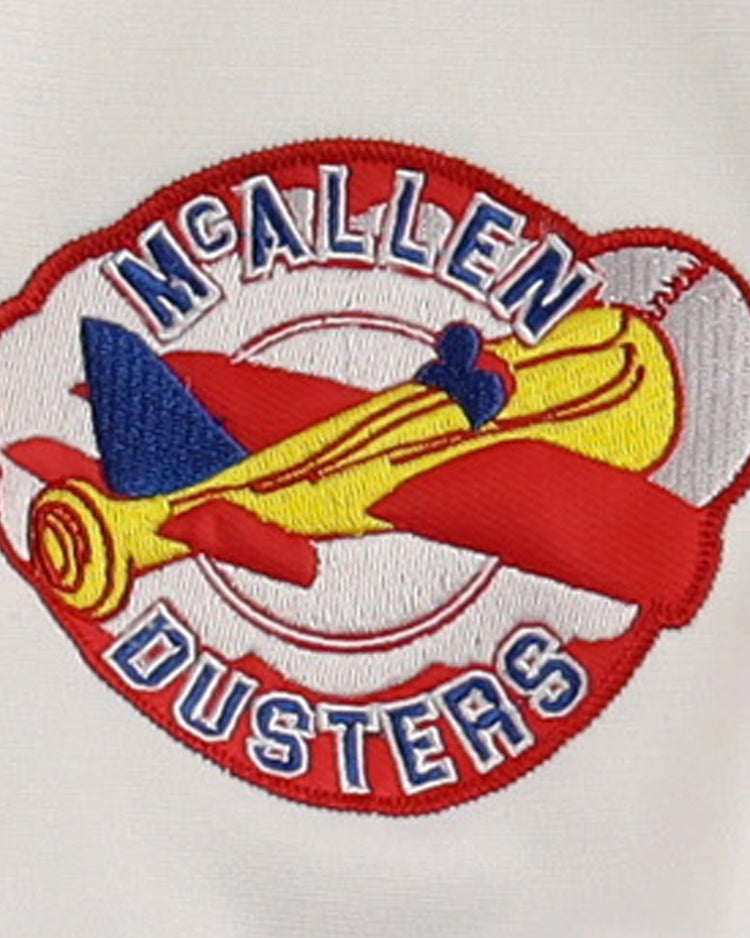 The EFF McAllen Dusters Lone Star Baseball Jersey features a yellow and red biplane embroidered with blue details and McALLEN DUSTERS in bold blue and white on a red and white background, celebrating local baseball pride.