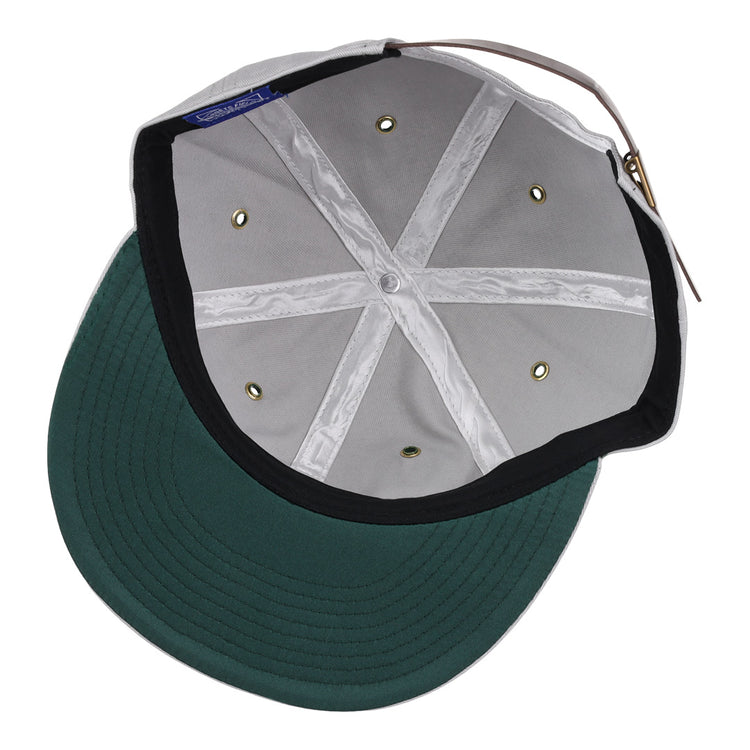 A look inside the EFF Magallanes Navigators Cotton Twill Ballcap reveals a green cotton twill visor, white crown with stitched seams, metal eyelets, and an adjustable back strap—classic details of Venezuelan baseball style.