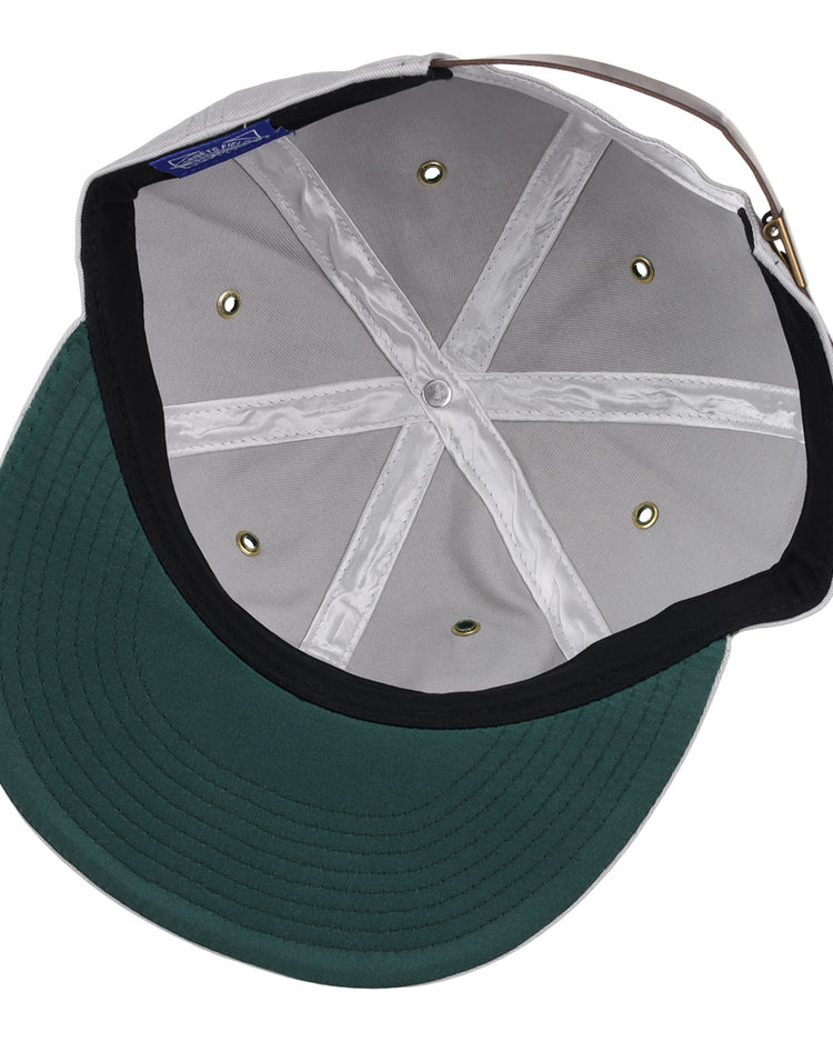 A look inside the EFF Magallanes Navigators Cotton Twill Ballcap reveals a green cotton twill visor, white crown with stitched seams, metal eyelets, and an adjustable back strap—classic details of Venezuelan baseball style.