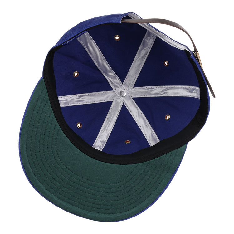 A close-up of the Montreal Royals Cotton Twill Ballcap by EFF shows its blue interior, green underbrim, metallic eyelets, white seam tape, brown adjustable strap, and classic Montreal Royals patch.