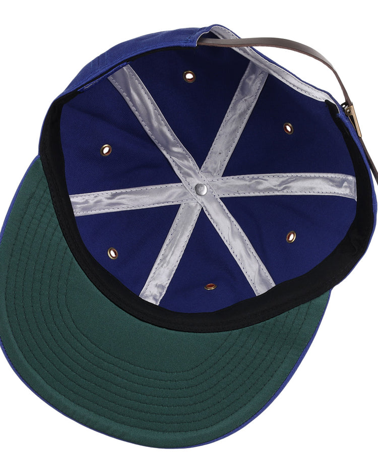 A close-up of the Montreal Royals Cotton Twill Ballcap by EFF shows its blue interior, green underbrim, metallic eyelets, white seam tape, brown adjustable strap, and classic Montreal Royals patch.