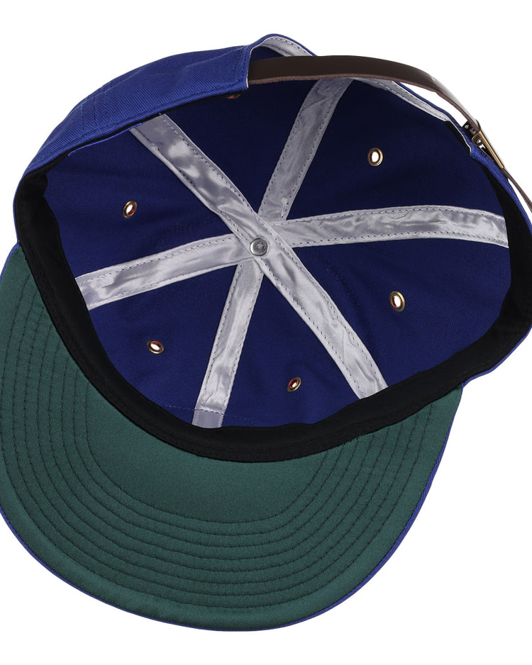 The EFF Reddy Kilowatt Cotton Twill Ballcap from the summer series is displayed inside-out, showing a green brim, black sweatband, silver seams, gold grommets, and an adjustable brown strap at the back.