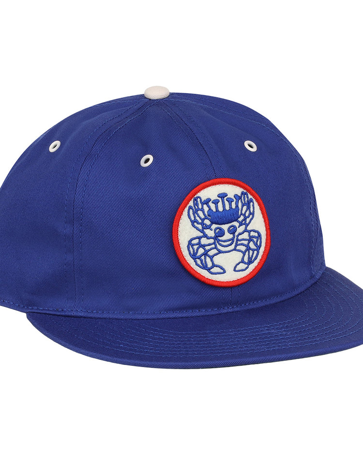 The EFF Santurce Cangrejeros Cotton Twill Ballcap is royal blue with a white and red patch showing a crowned blue cartoon crab, plus white eyelets and a top button—ideal for fans of the Cangrejeros.