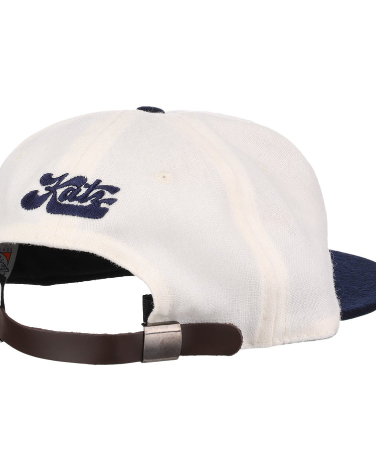 The EFF Kansas City Katz Off White Vintage Inspired Ballcap features a navy brim, brown adjustable strap with metallic clasp, and blue Katz embroidery above the back opening.