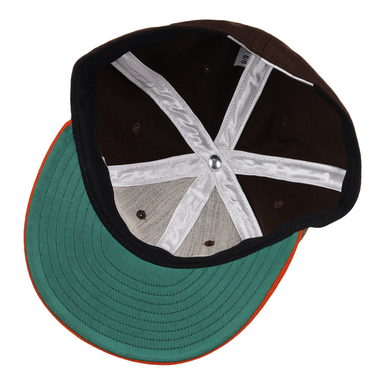 The image shows the inside of an EFF Pine Bluff Judges 1953 Vintage Ballcap, featuring a green brim with orange edge, brown panels, white cross-shaped stitching, and a silver button.