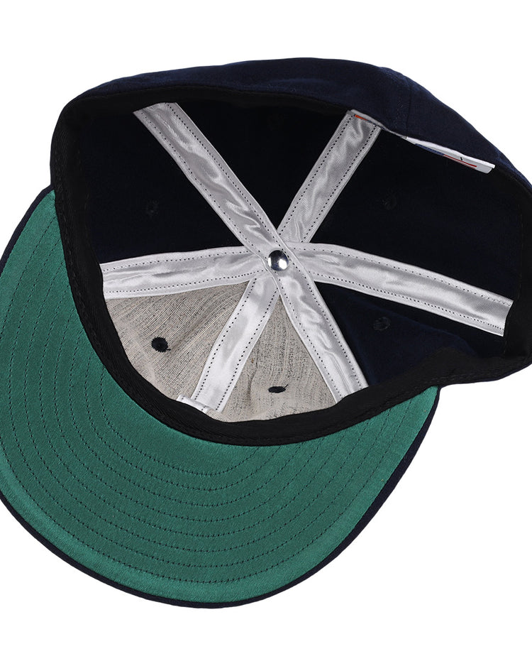 The image displays the inside of the EFF Twin Falls Cowboys 1947 Vintage Ballcap, featuring a green underbrim, gray wool crown panels, white inner seams, and a silver top button—all crafted from genuine baseball cloth.
