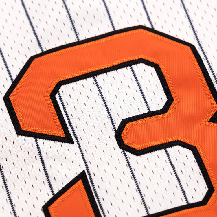 Close-up of an orange number 3 with a black outline stitched onto a white EFF Sioux City Ghosts Pinstripe Button Down Jersey, featuring thin vertical navy blue pinstripes.