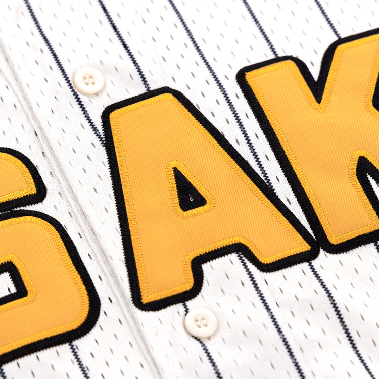 The EFF Osaka Tigers EFF Pinstripe Button Down Jersey features white pinstripes, bold yellow and black A K lettering, and two white buttons on the front placket, inspired by the Osaka Tigers.